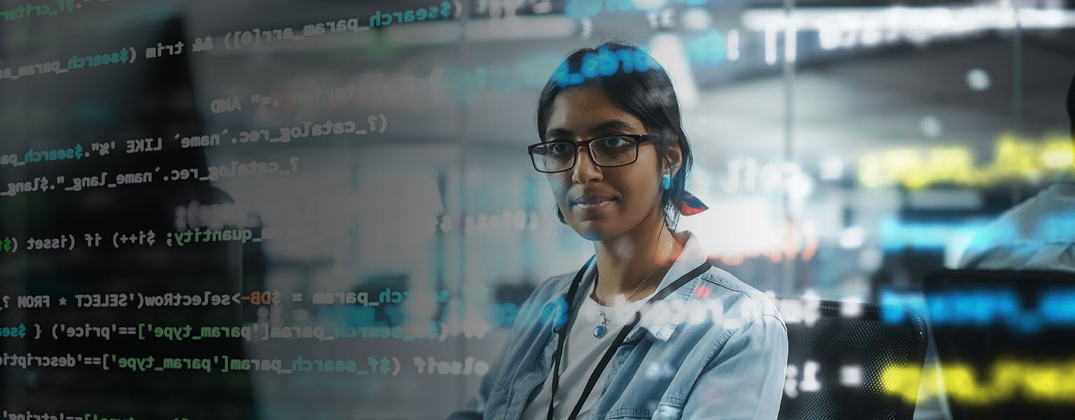 Image of development code on a computer screen superimposed over an indian business woman